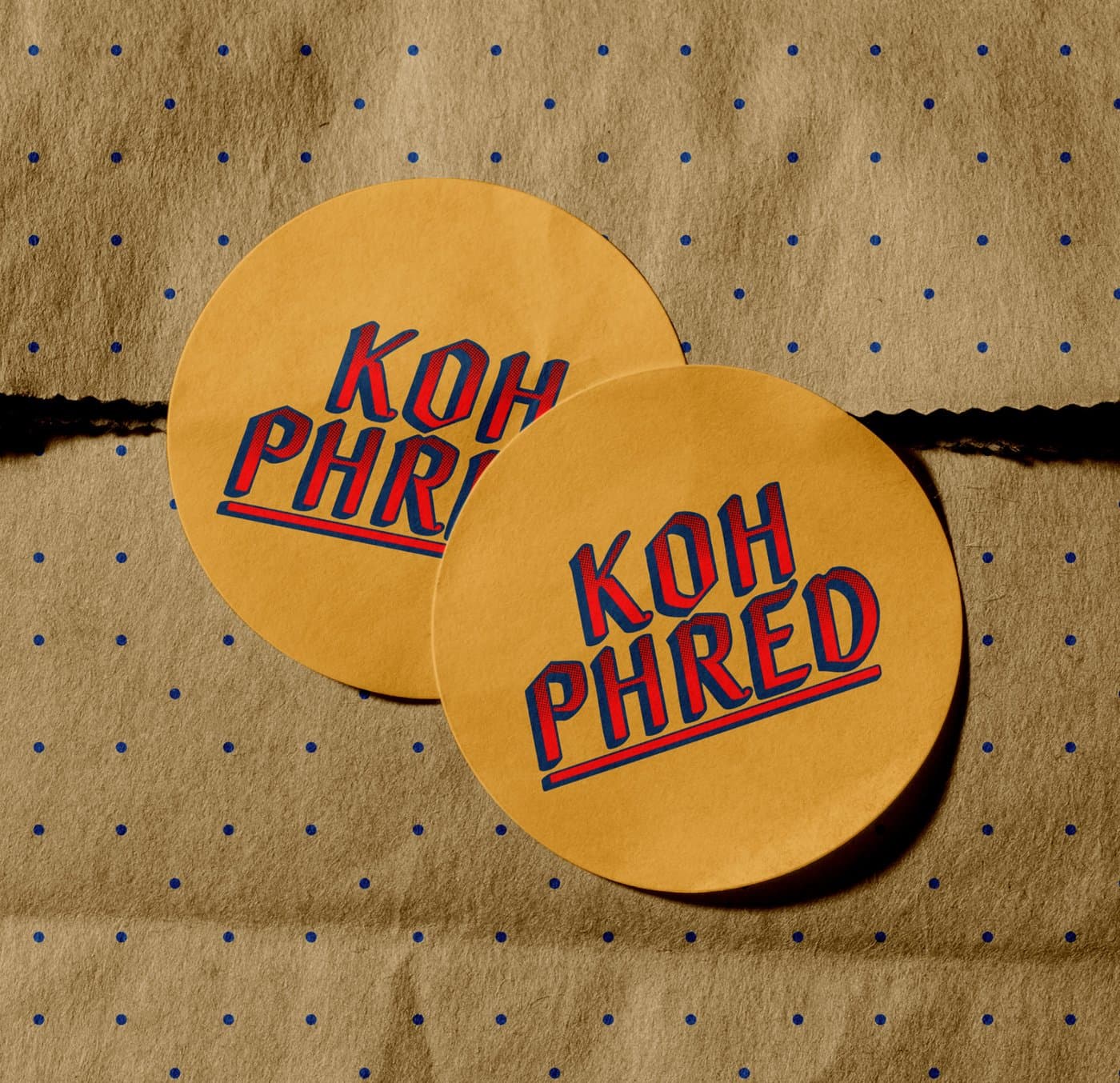 Two round Koh Phred logo stickers on a kraft paper bag